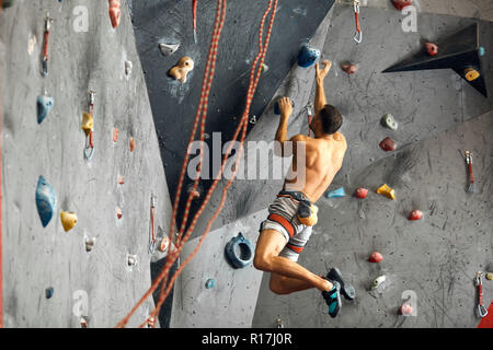 Panoramablick mann Bouldern in einer Kletterhalle. Stockfoto