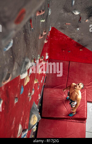 Panoramablick mann Bouldern in einer Kletterhalle. Stockfoto