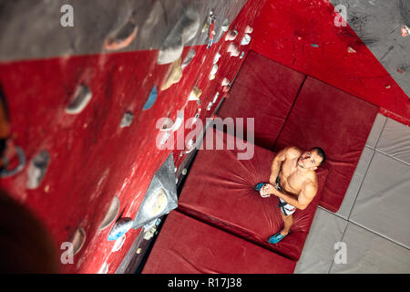 Panoramablick mann Bouldern in einer Kletterhalle. Stockfoto