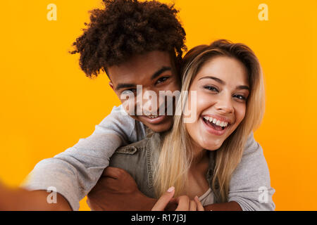 Bild von glücklich nette junge Liebende Paar über gelben Hintergrund umarmen isoliert posiert ein selfie durch die Kamera. Stockfoto