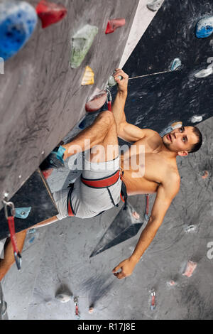 Männliche professioneller Bergsteiger an Indoor Training zu Bouldern. Stockfoto