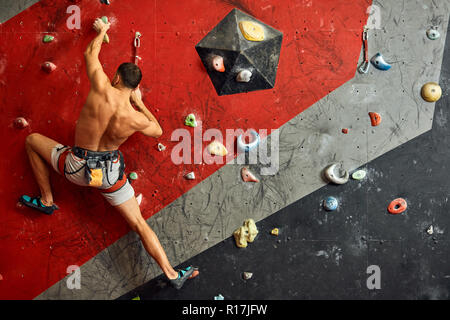 Männliche professioneller Bergsteiger an Indoor Training zu Bouldern. Stockfoto