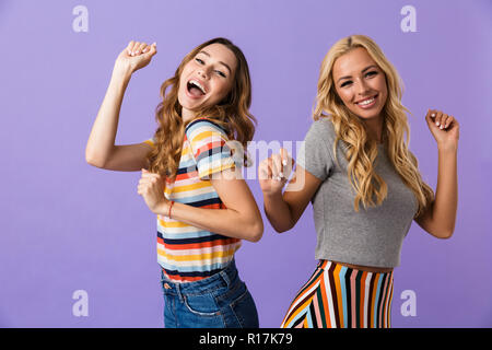 Zwei hübsche junge Mädchen Freunde stehen über violette Hintergrund isoliert, Tanzen Stockfoto