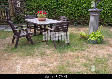 Gartentisch und Stühlen auf einem Rasen mit toten trocken Patches während eines Sommers Dürre, Berkshire, Juli Stockfoto