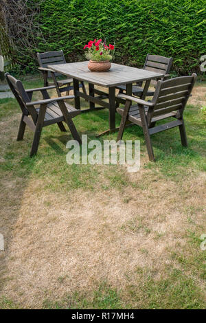 Gartentisch und Stühlen auf einem Rasen mit toten trocken Patches während eines Sommers Dürre, Berkshire, Juli Stockfoto