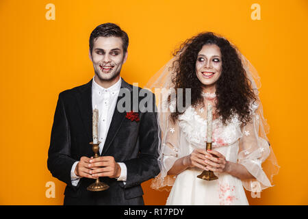 Glückliches Paar in Scary Haloween Kostüme auf gelben Hintergrund gekleidet Stockfoto