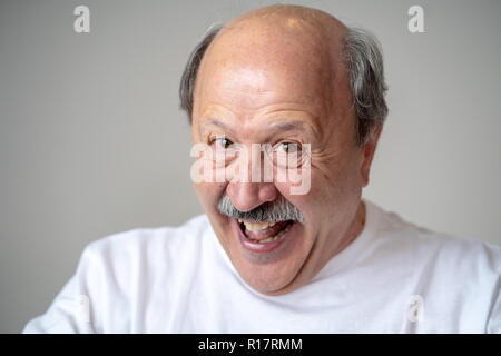 Lächeln und Lachen 60er Jahre alten älterer Mann candid Nahaufnahme portrait in menschliche Gefühle und Mimik Konzept in neutralen Hintergrund isoliert. Stockfoto