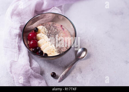 Lecker smoothy zum Frühstück mit Chia auf Violett und Lila Hintergrund mit Banane, Kirsche und schwarze Johannisbeere Stockfoto