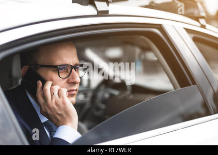 Junge erfolgreiche Geschäftsmann am Telefon sitzen auf dem Rücksitz einer Elite Auto, Vorträge und Tagungen Stockfoto