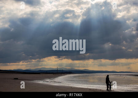 Leeren Strand an einem düsteren Moody Tag mit Sonnenstrahlen, die durch die stürmischen Wolken. Prestatyn und die Berge von Snowdonia sind sichtbar in den hinterg Stockfoto