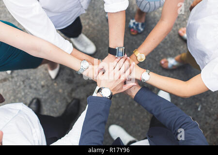 Business, Menschen und Teamarbeit Begriff - lächelnde Gruppe von Geschäftsleuten stehen im Kreis und die Hände übereinander Stockfoto