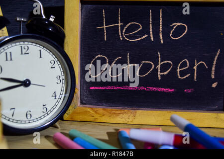 Hallo Oktober auf Phrase bunte handschriftlich auf der Tafel. Die Bereiche Bildung und Business Konzept. Wecker, Kreide, Bücher auf schwarzem Hintergrund Stockfoto