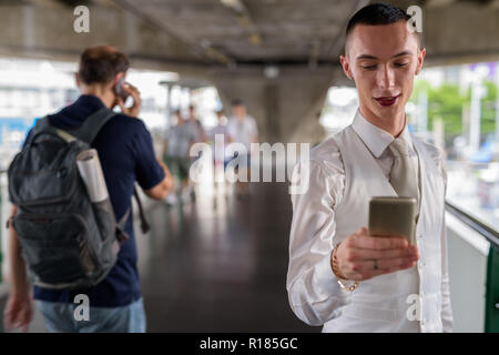 Junge androgyne homosexuellen LGTB Geschäftsmann mit Mobiltelefon Stockfoto