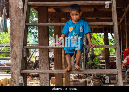 Thakhek, Laos - 21. April 2018: Barfuß Kind auf der Treppe von einer Abgelegenen ländlichen Dorf in der Khammouane Provinz in Laos sitzen Stockfoto