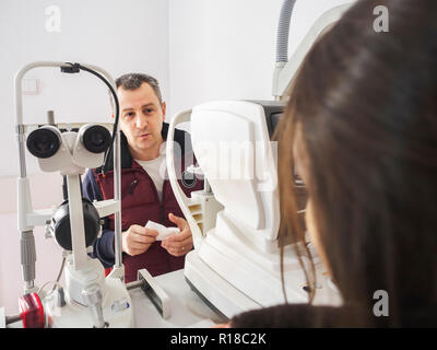 Man spricht mit dem Augenarzt während einer Augen Untersuchung mit der Spaltlampe. Augen Klinik untersuchen. Stockfoto