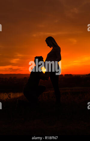 Silhouetten der Mann küssen Magen von seiner schwangeren Frau, während Sie genießen die Zeit zusammen im Freien. getönten Bild. Stockfoto