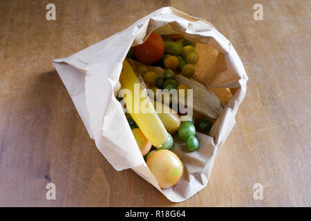 Reifung grüne Tomaten in eine braune Papiertüte, mit banana skins. Stockfoto