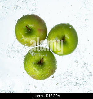 Grüne Äpfel mit Wasser spritzen auf weißem Hintergrund Stockfoto