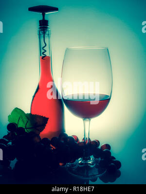 Wein in einem Glas neben einer Flasche Wein und Trauben auf einem Tisch mit Überlegungen über einen vintage Wand Hintergrund Stockfoto