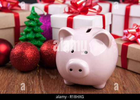 Piggy Bank mit vor dem Hintergrund von Weihnachten Spielzeug und Geschenkboxen Stockfoto