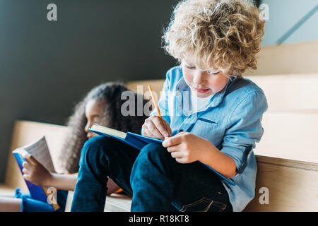 Konzentriert multiethnischen Schüler schriftlich bei Notebooks. Stockfoto