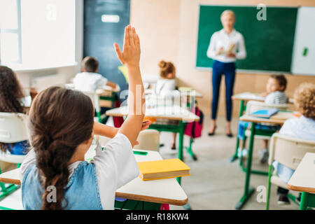 Ansicht der Rückseite des Schülerin Hand zu beantworten Lehrer während der Lektion Frage Stockfoto