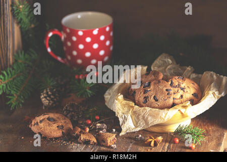 Weihnachten und neues Jahr Komposition mit köstlichen Schokolade Cookies, Erdnüssen und Tasse Kaffee oder Tee, Niederlassungen Fichte und kiefer Kegel auf dunklen Holz- b Stockfoto