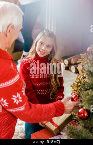 Ältere Menschen schmücken Weihnachtsbaum mit seiner Enkelin Stockfoto