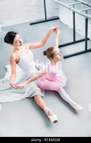 Hohe Betrachtungswinkel von Erwachsenen ballerina Trainieren mit niedlichen Kind im rosa Tutu in der Ballettschule Stockfoto