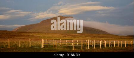 Ein Sommernachtstraum in Island. Ein Berg leuchtet in der Mitternachtssonne. Eine Wolke an der Spitze des Berges. Stockfoto