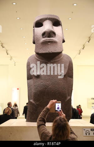 Frau, die mit ihrem Telefon ein Foto der aus Basalt gefertigten Statue von der Osterinsel macht, die im British Museum, London, Großbritannien, ausgestellt ist Stockfoto