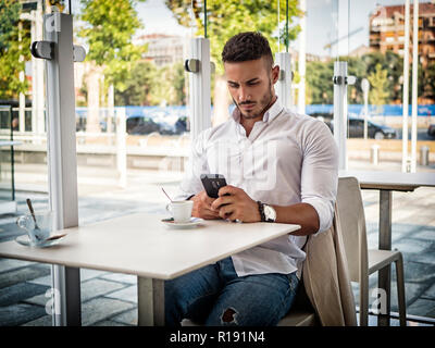 Nahaufnahme von gutaussehenden jungen Mann Kaffee trinken im Shop bei Handy suchen Stockfoto