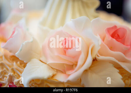 Schöne große Hochzeitstorte mit drei Geschichte durch Ausschreibung süße Rosen im Freien eine weisse Hochzeitstorte mit drei Ebenen und roten Rosen dekoriert Stockfoto