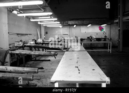 Schwarz-weiß Foto des verlassenen und traditionelle Werkstatt. Nähen und Färben Kleidung und Jeans mit Rosen an der Wand. Stockfoto