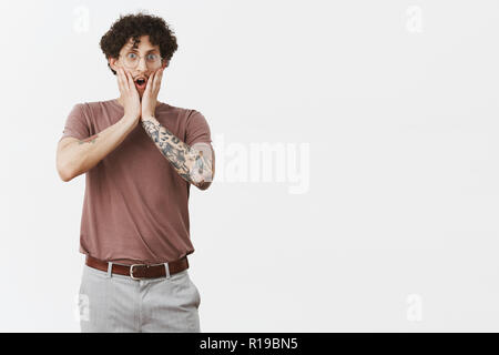 Mann, du musst mich verarschen. Portrait von überrascht sprachlos hübscher junger curly-haired Kerl in Gläser mit niedlichen Schnurrbart und Tattoos fallen Kiefer Stockfoto