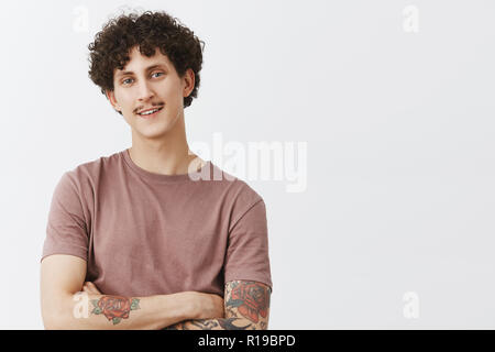 Beeindruckt Freund stolz von Freundin zu verbessern. Portrait von zufrieden und freuen uns sehr hübscher junger Mann mit Schnurrbart Tattoos und Curly Hai Stockfoto