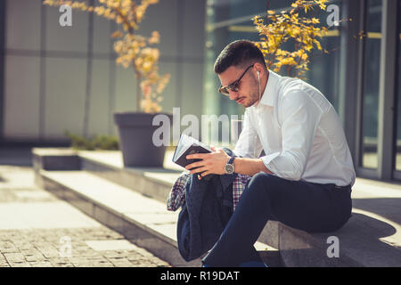 Ein beredtes Geschäftsmann außerhalb ist, genießt er in der schönen Wetter, während das Notebook suchen Stockfoto