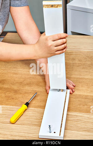 Der Heimwerker verbindet zusammen, die die zwei Teile des Ready-to-Möbel mit Cam schraube Befestigungen und hölzernen Paßstift, Flat Pack Möbel zusammenbauen. Stockfoto