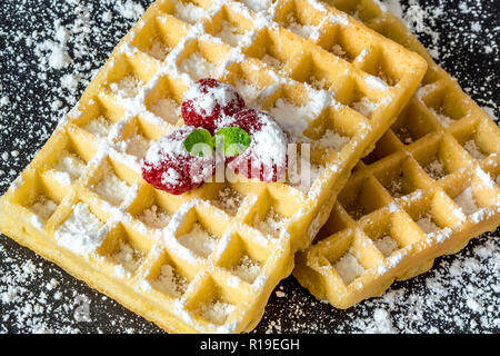 Sweet Toast, Waffeln mit Himbeeren und einem Zweig Minze und Zucker Pulver Nahaufnahme Makro auf schwarzem Hintergrund Stockfoto