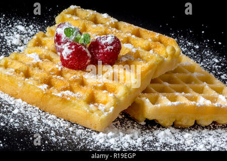 Sweet Toast, Waffeln mit Himbeeren und einem Zweig Minze und Zucker Pulver Nahaufnahme Makro auf schwarzem Hintergrund Stockfoto