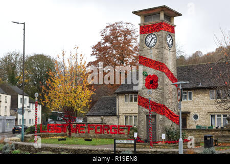 Clock Tower Kriegerdenkmal in der Mitte des Cotswold Stadt Nailsworth ist gestrickt Roter Mohn Erinnerung Sonntag zu gedenken geschmückt Stockfoto