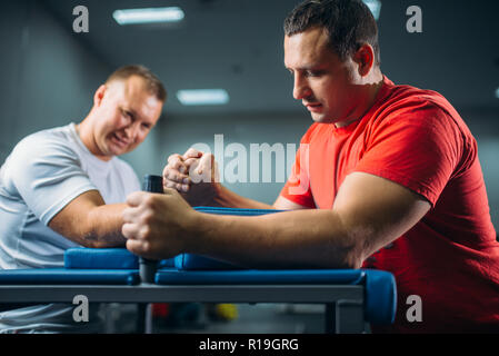 Zwei Arm Ringer auf ihren Händen am Tisch mit Stiften, Schlacht in Action kämpfen, ringen Wettbewerb. Ringen Herausforderung, power Sport Stockfoto