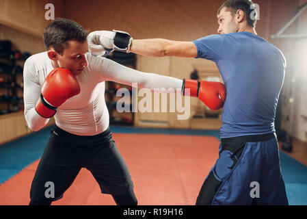 Zwei männliche kickboxers in Handschuhe üben am trainieren Sie im Fitnessraum. Kämpfer auf Training, Kickboxen Praxis in Aktion, sparring Partner Stockfoto