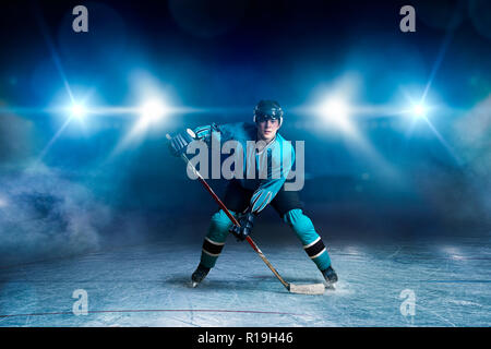 Hockey Player mit Stick auf Eis, spiel Konzept, Strahler auf dunklem Hintergrund. Männliche Person im Helm, Handschuhe und einheitliche, extreme Sport Stockfoto