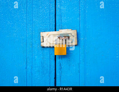 Geschlossenes Vorhängeschloss mit Kette am blauen Holztür strukturierten Hintergrund Stockfoto