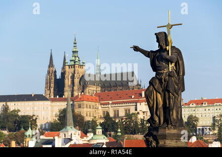 Skulptur des Heiligen Johannes des Täufers auf der Karlsbrücke, auf der Prager Burg und der St. Veits Kathedrale im Hintergrund, Prag, Tschechische Republik, sonnigen d Stockfoto