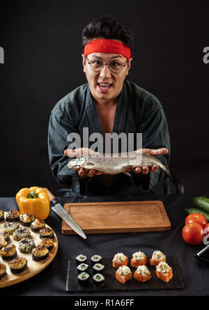 Stattliche assian Chef mit Fisch auf Händen auf der Suche nach einem die Kamera Stockfoto