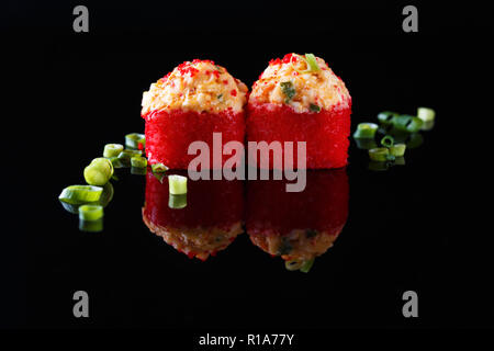 Appetitlich gebackene Sushi Roll mit Fisch, grüne Zwiebeln auf einem schwarzen Hintergrund mit Reflexion Menü und Restaurant Konzept kopieren Raum Stockfoto