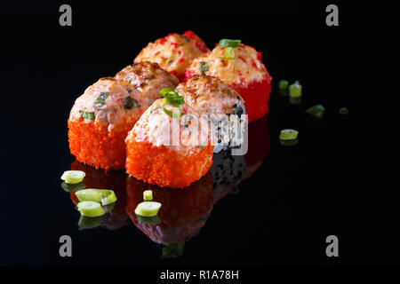 Köstliches Sushi Roll mit Fisch auf einem schwarzen Hintergrund mit Reflexion Menü und Restaurant Konzept kopieren Raum Stockfoto