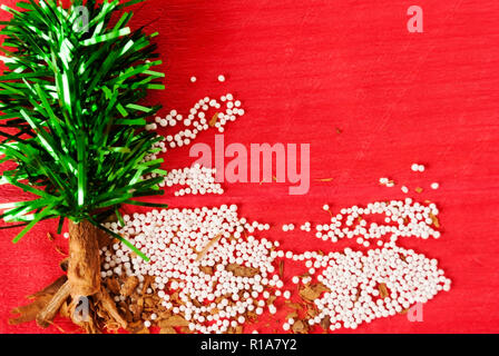 Weihnachtsbaum mit Zimt und grüne Zweige aus Kunststoff mit weißen Kugeln von künstlichen Schnee auf rotem Hintergrund gemacht Stockfoto